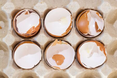box with broken eggshell brown chicken eggs, background texture pattern