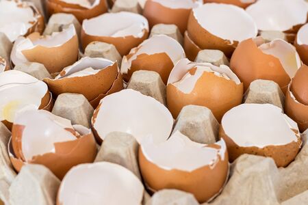 box with broken eggshell brown chicken eggs, background texture patternの写真素材