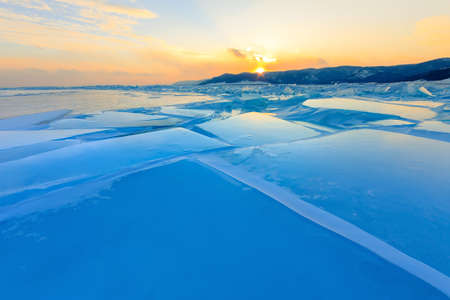 Transparent blue hummocks Baikal ice is shining through the crack sunsetの写真素材
