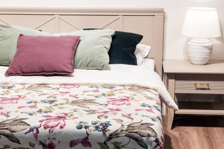 Bedroom interior, bed with pillows and blanket, lamp is on the bedside table