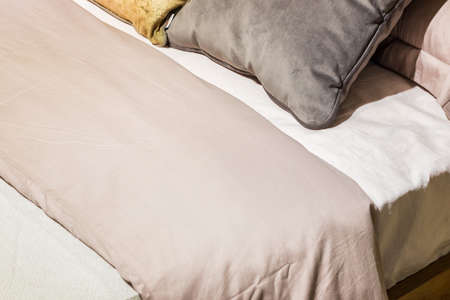 Bedroom interior, bed with pillows and blanket, lamp is on the bedside table