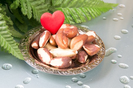 Brasil nuts on the plate and green leafsの写真素材
