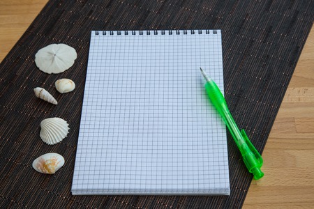 Blank notepad with pen and sea shells on the tableの写真素材