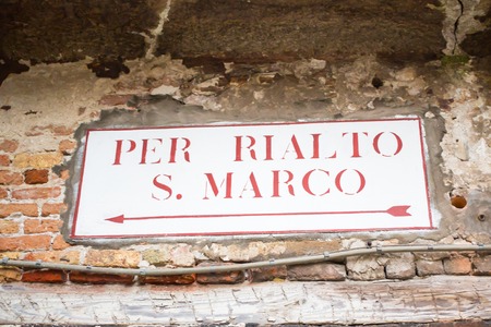 Directional sign to San Marco square and Rialto on old Venetian buildingの写真素材