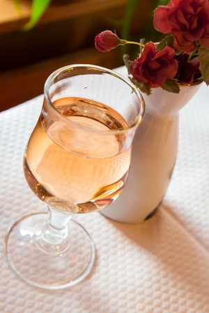 glass with rose wine and flower on the tableの写真素材