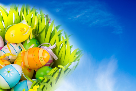 Green grass box full of Easter eggs on the blue sky with clouds backgroundの写真素材