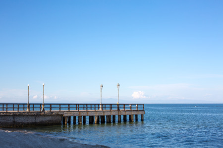 Seascape with Wooden pier or jetty on a blue sky background. Paralia, Greece. Place for textの写真素材
