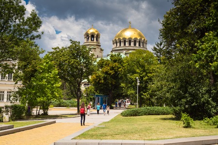 Sofia, Bulgaria - June 4, 2015: Golden domes of St. Alexander Nevsky Cathedral in the center of Sofia, capital of Bulgaria, green trees and people walking in the parkのeditorial素材