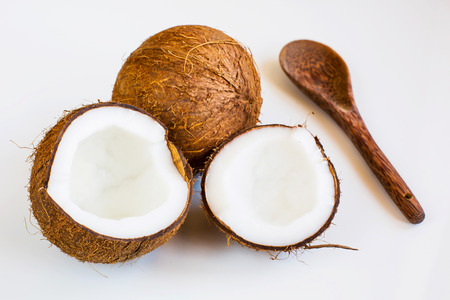Two parts of ripe Fresh coconut, whole fruit behind and coconut made spoon on white background