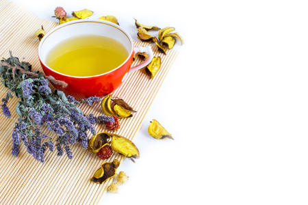 Herbal tea in red cup, dry marjoram herbs and dry flower petals on bamboo mat background. Copyspaceの写真素材