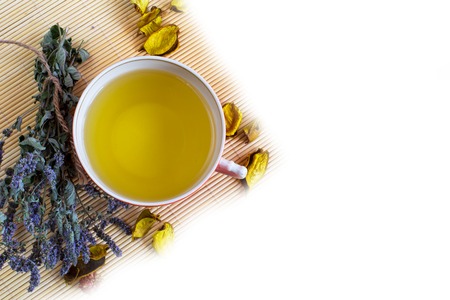 Top view of Herbal tea in red cup, dry marjoram herbs and dry flower petals on bamboo mat background. Copyspaceの写真素材