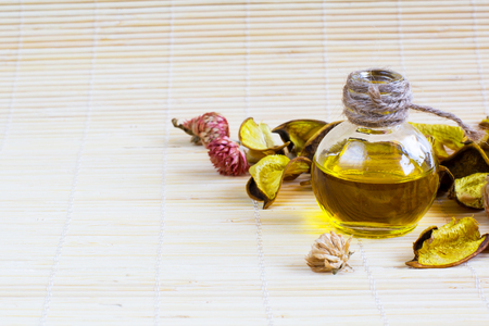 Still life with Essential or cosmetic oil bottle, dry flower petals on the bamboo mat backgroundの写真素材