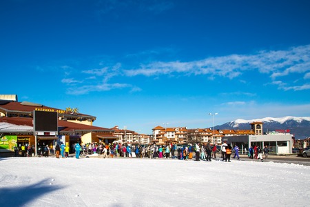 Bansko, Bulgaria - February 19, 2015: Bansko ski station, cable car lift and people waiting in line near it in Bansko, Bulgaria. Snow mountain peaks and blue sky at the backgroundのeditorial素材