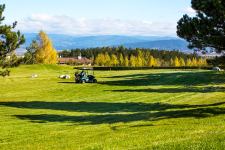 Bansko, Bulgaria - October, 31, 2015: Pirin Golf Club panorama, golf cart,  green grass field, colorful trees, blue skyのeditorial素材