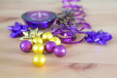 Still life with Christmas holiday decoration, purple and yellow golden sweet candy balls, candle in the backgroundの写真素材