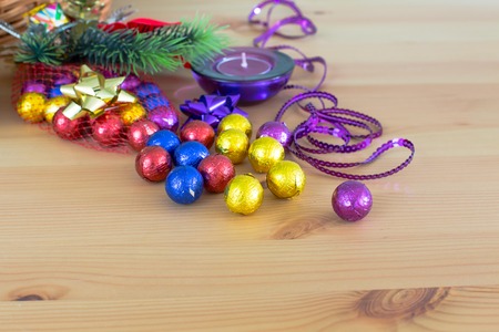 Still life with Christmas holiday decoration, purple and yellow golden sweet candy balls, candle, pine tree branch background with copy spaceの写真素材