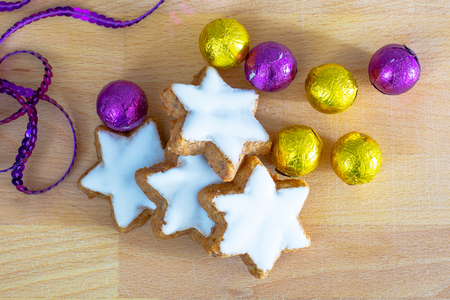 Still life with holiday decoration, star shape Christmas cookies, purple and yellow golden sweet candy balls close upの写真素材