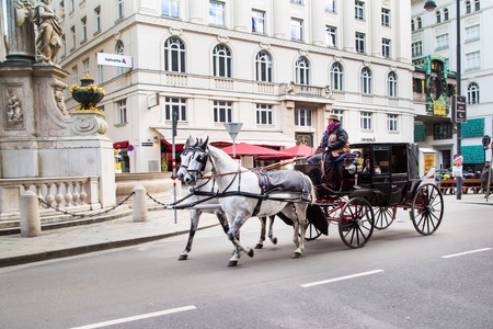 Vienna, Austria - April 3, 2015: City center street view, people walking, Vienna clock and fiaker with white horses  in Vienna, Austriaのeditorial素材