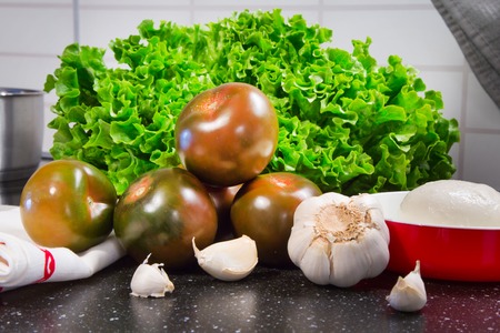 Vegetables still life with tomatoes, lettuce, garlic, mozarella prepared for cookingの写真素材