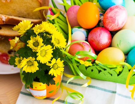 Still life with Nice spring yellow flowers, colorful Easter eggs and traditional Easter cakeの写真素材