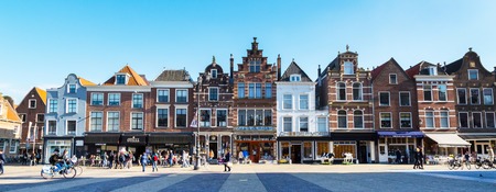 Delft, Netherlands - April 8, 2016: Colorful street panoramic view with traditional dutch houses on the square, bicycles, people walking in downtown of popular Holland destinationのeditorial素材