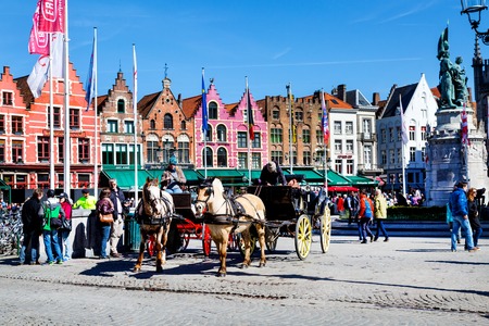 Bruges, Belgium - April 10, 2016: Market place or Grote Markt square with colorful traditional houses, fiaker, people walking in popular belgian destinationのeditorial素材