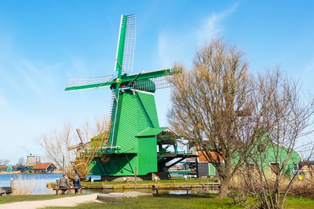 Zaanse schans, Netherlands - April 1, 2016: Green windmill in Zaanse Schans, North Holland, traditional village, tourists, blue skyのeditorial素材
