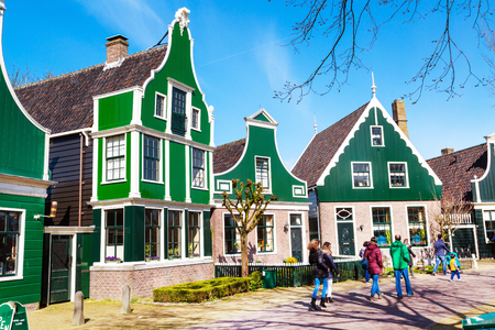 Zaanse schans, Netherlands - April 1, 2016: Zaanse Schans, traditional village, tourists walking, North Holland, green houses against blue cloudy skyのeditorial素材