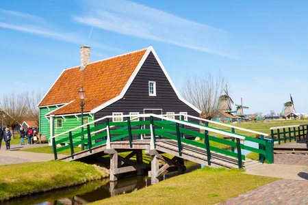 Zaanse schans, Netherlands - April 1, 2016: Zaanse Schans, North Holland, traditional village, tourists, green houses and windmills against blue cloudy skyのeditorial素材