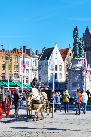 Bruges, Belgium - April 10, 2016: Market place or Grote Markt square with colorful traditional houses, fiaker, people in popular belgian destinationのeditorial素材