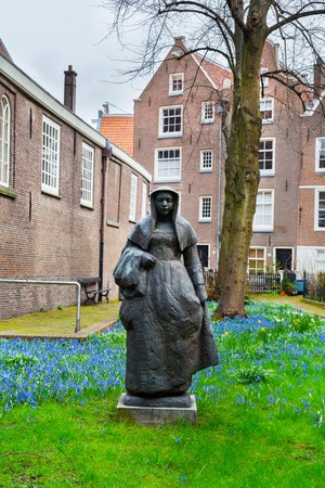 Amsterdam, Netherlands - March 31, 2016: Begijnhof courtyard with nun statue and garden surrounded by historic houses in Amsterdam, Netherlandsのeditorial素材