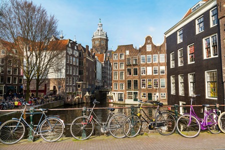 Amsterdam, Netherlands - April 2, 2016: Traditional old buildings, church, canal and bridge view with bicycles in Amsterdam, the Netherlandsのeditorial素材