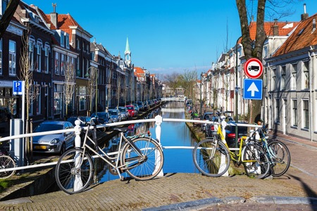 Delft, Netherlands - April 8, 2016: Colorful street view with traditional dutch houses, bicycles, canal in downtown of popular Holland destinationのeditorial素材