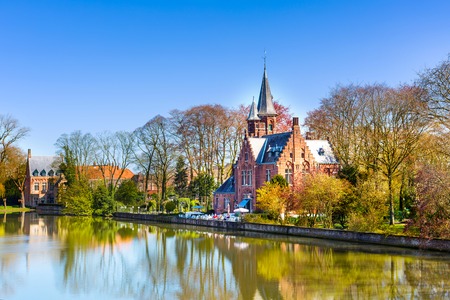 Minnewater lake panorama, reflection of gothic Flemish style building, blue sky, Bruges, Belgiumの写真素材