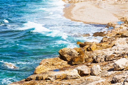 Nature blue turquoise summer sea vacation background with waves on stone beach shore close upの写真素材