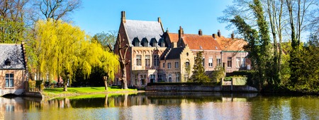 Bruges, Belgium panorama with lake and medieval houses against blue skyの写真素材