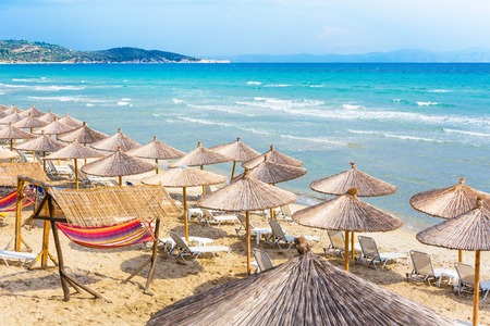 Summer greek beach vacation background with turquoise sea water waves and umbrellas, Greeceの写真素材