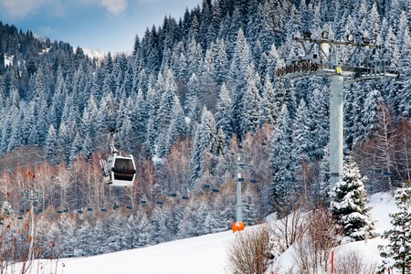 Ski lift and snow covered mountains with pine trees background at ski resortの写真素材