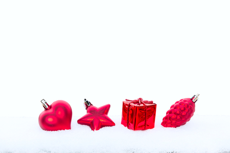 Christmas holiday decorations, red heart, pine cone and gift in the snow on white backgroundの写真素材