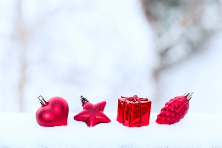 Christmas holiday red decorations, heart, pine cone and gift in the snow on blured white backgroundの写真素材