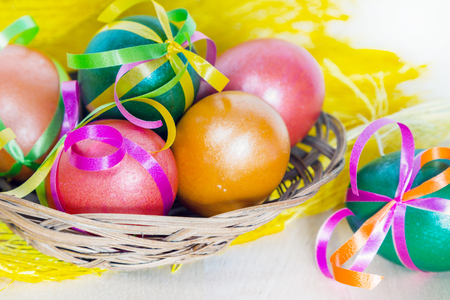 Brightly colored bow decorated easter eggs in basket, holiday backgroundの写真素材