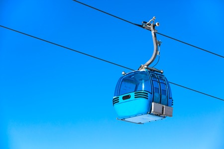 Blue cable car cabin ski lift and blue sky at the background