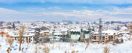 Houses with snow roofs and church tower panorama banner of bulgarian ski resort Bansko, Bulgaria