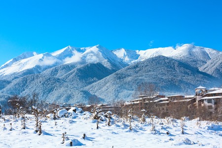 Winter travel vacation nature panoramic background with snow covered mountain peaks and snow roofs, Pirin, Bulgariaの写真素材