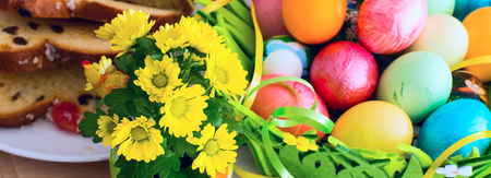 Easter banner background with spring yellow flowers, colorful Easter eggs and traditional Easter cakeの写真素材