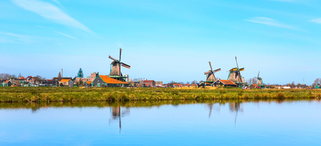 Panoramic view of windmills in Zaanse Schans, traditional village in Holland, reflection in lake, blue sky, copy spaceの写真素材