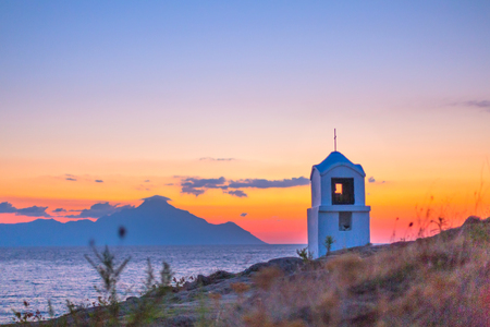 Small greek chapel and silhouette of mount Athos at sunrise or sunset colorful sky in Greeceの写真素材