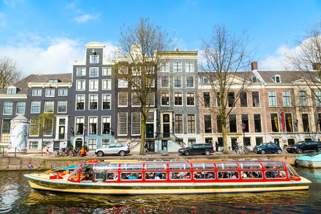 Amsterdam, Netherlands - April 2, 2016: Traditional old buildings, canal and boat with tourists in Amsterdam, Netherlandsのeditorial素材