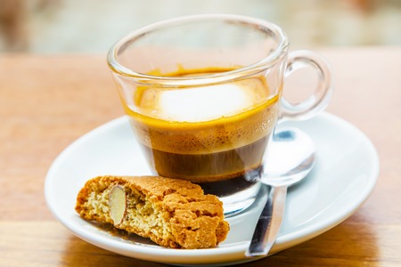 Macchiato coffee in the small glass cup and piece of nut cakeの写真素材