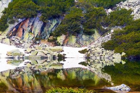 spring lake landscape with snow, colorful rocks and reflection in waterの写真素材